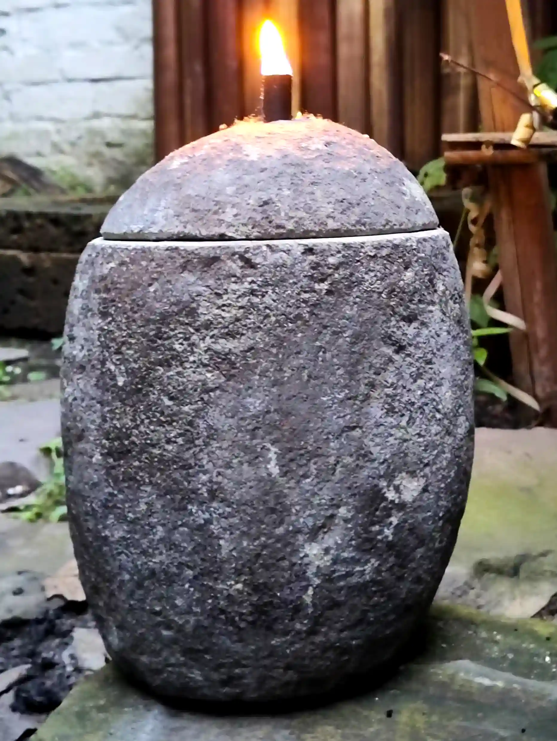 Ovale Steinlampe aus Naturstein mit Flamme als stimmungsvolle Außenbeleuchtung.