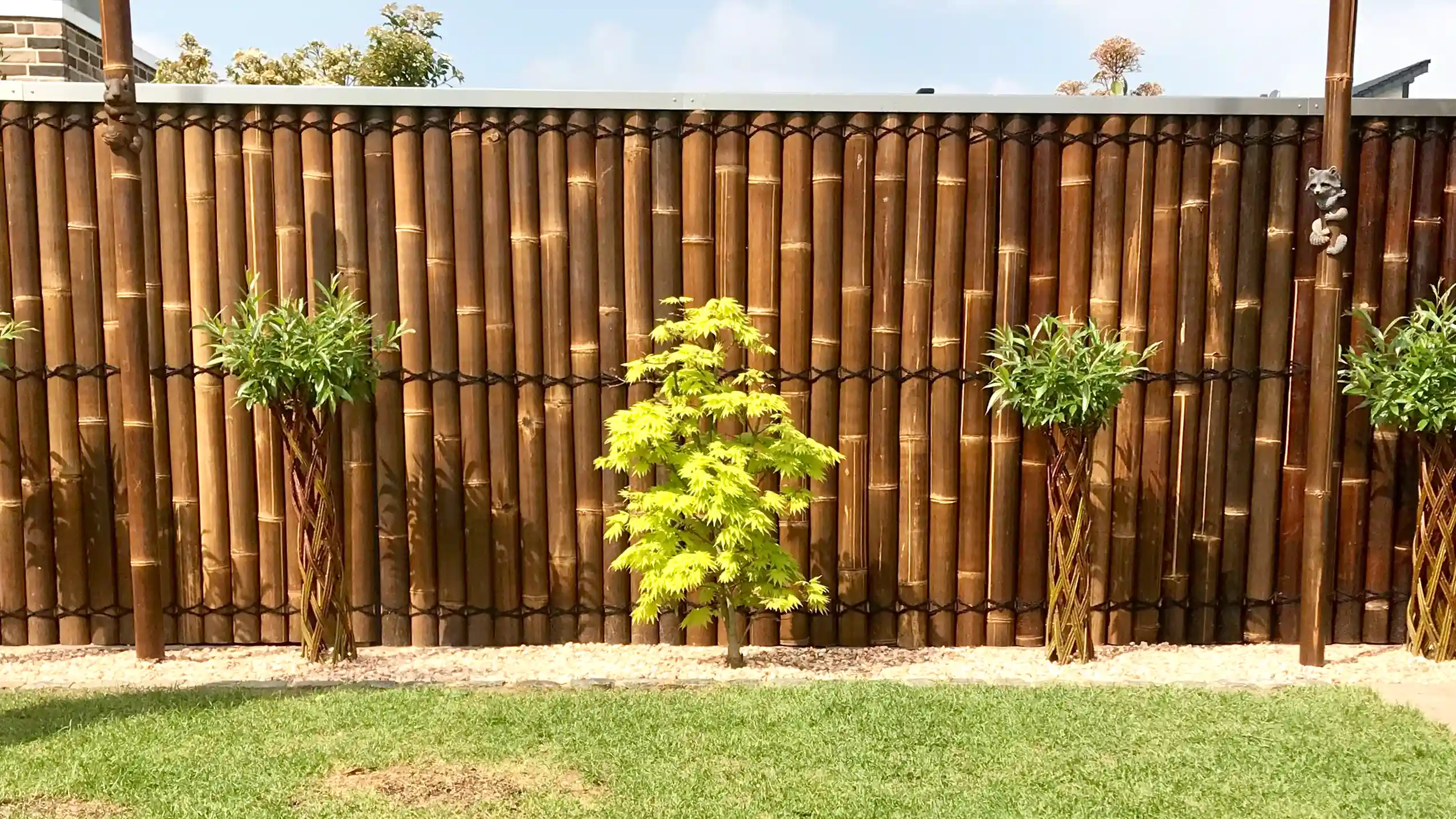Aufgestellter Bambushalbzaun Wulung als Sichtschutzzaun im Garten mit Rasen und Pflanzen.