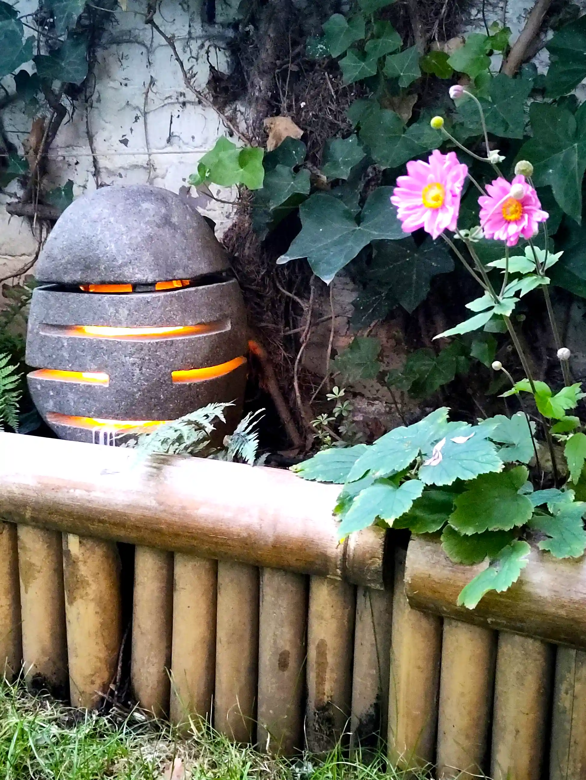 Natursteinlampe mit seitlichen Lichtschlitzen als dekorative Beleuchtung im Garten.